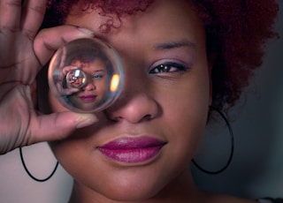 woman holding covering right eye with clear glass ball