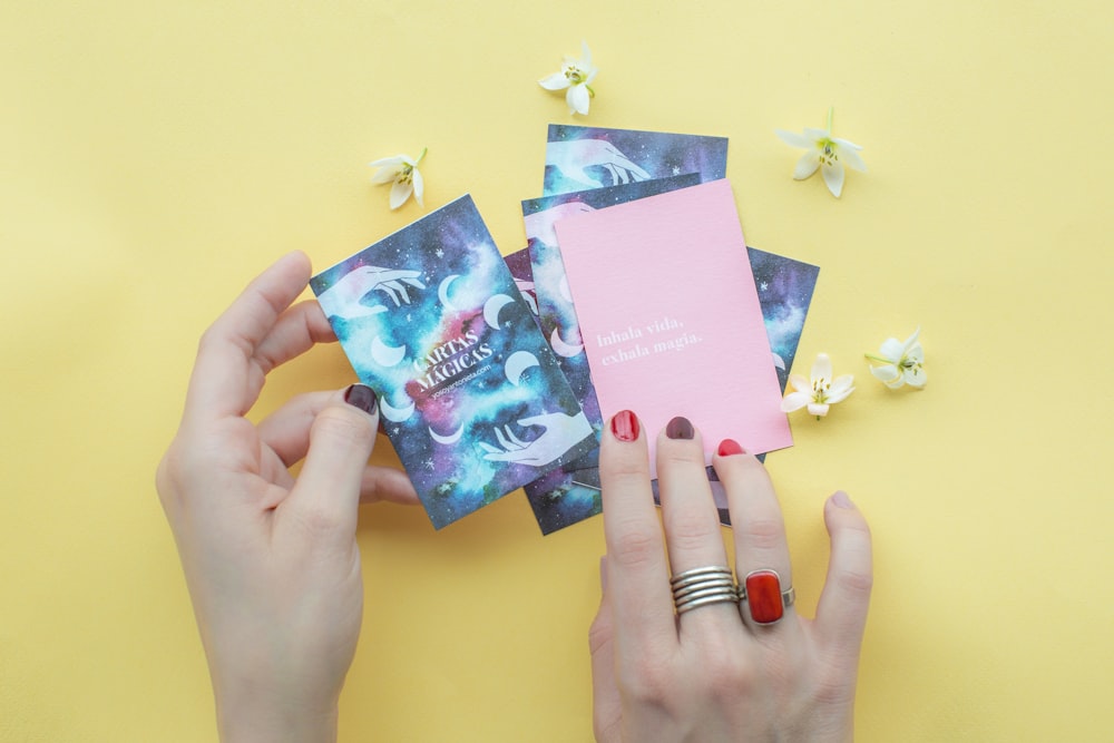 person holding blue and pink books