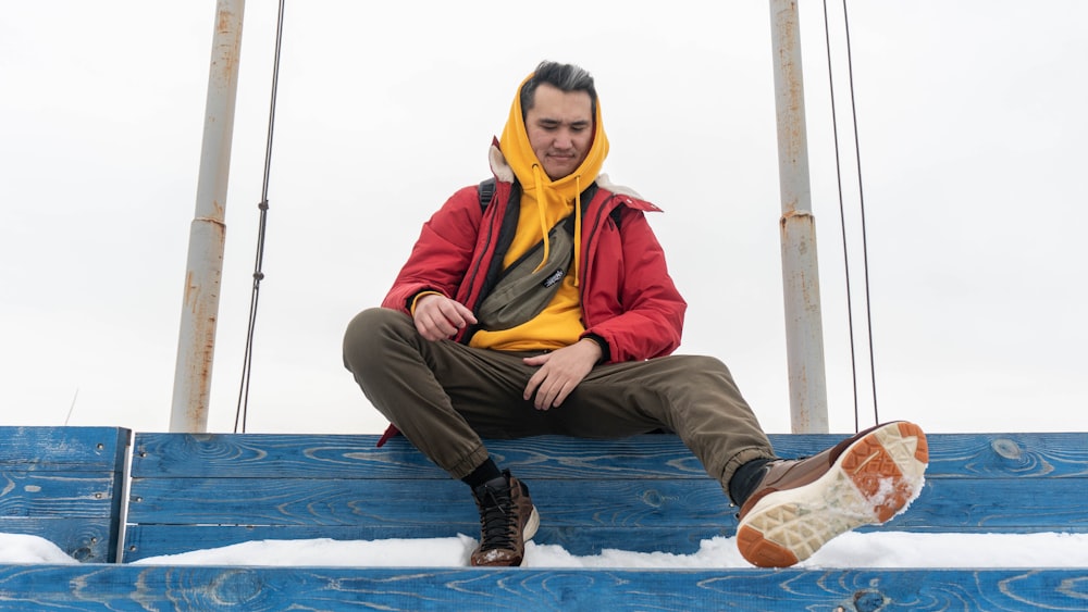 man sitting on blue wooden rail