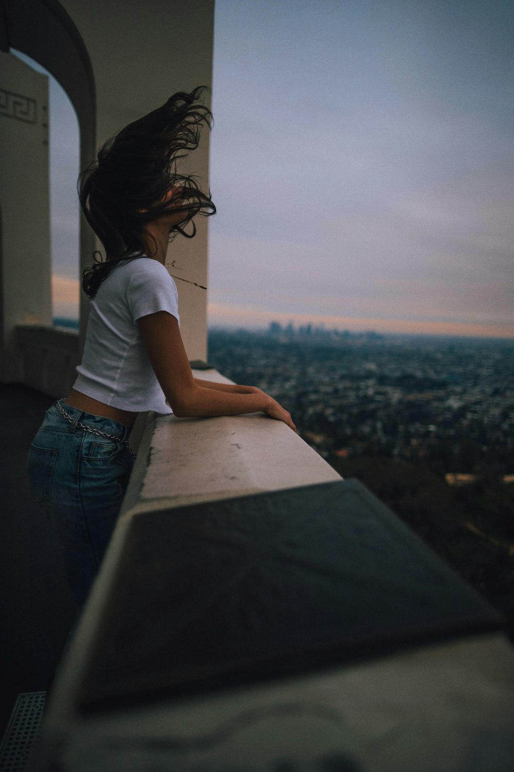 femme s’appuyant sur la rampe en béton du balcon