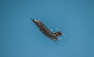 A sleek airplane soaring above Somali landscapes under a clear blue sky.