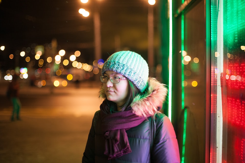 person standing beside glass wall with bokeh lights
