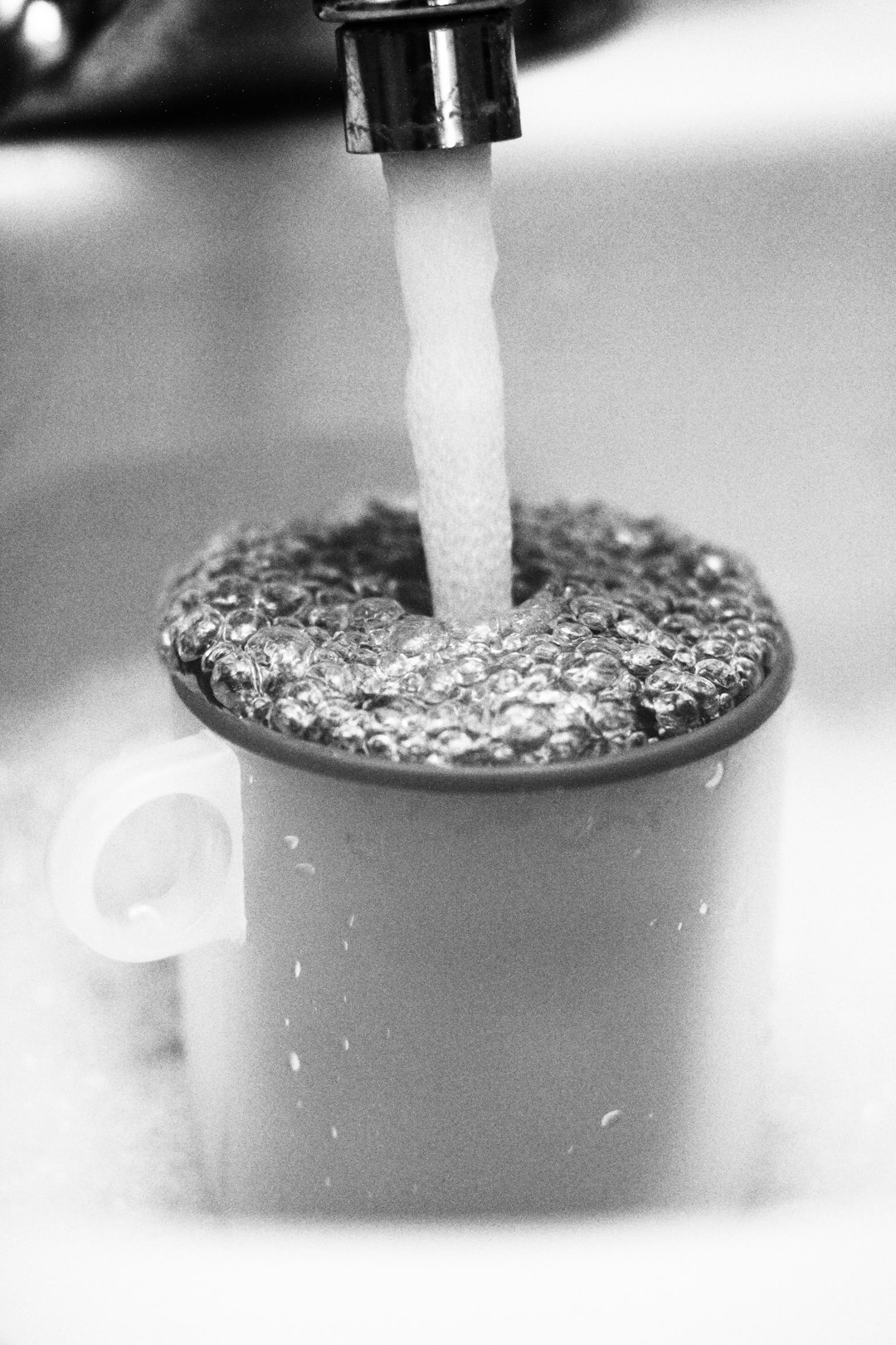 grayscale photo of water pouring in container