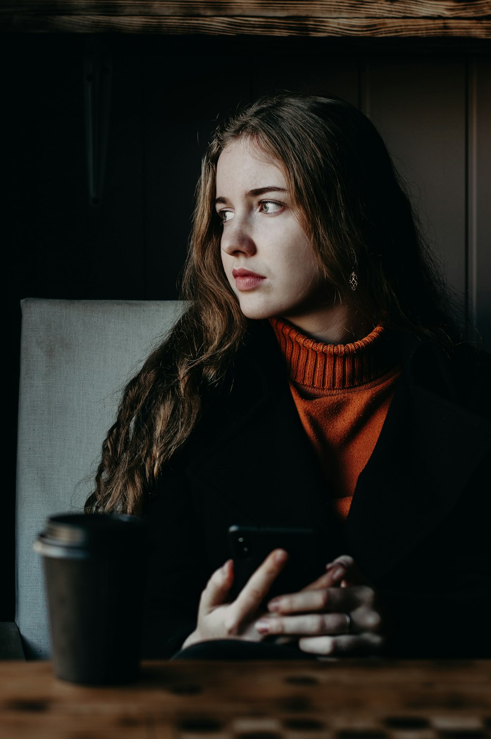 woman wearing black jacket holding smartphone