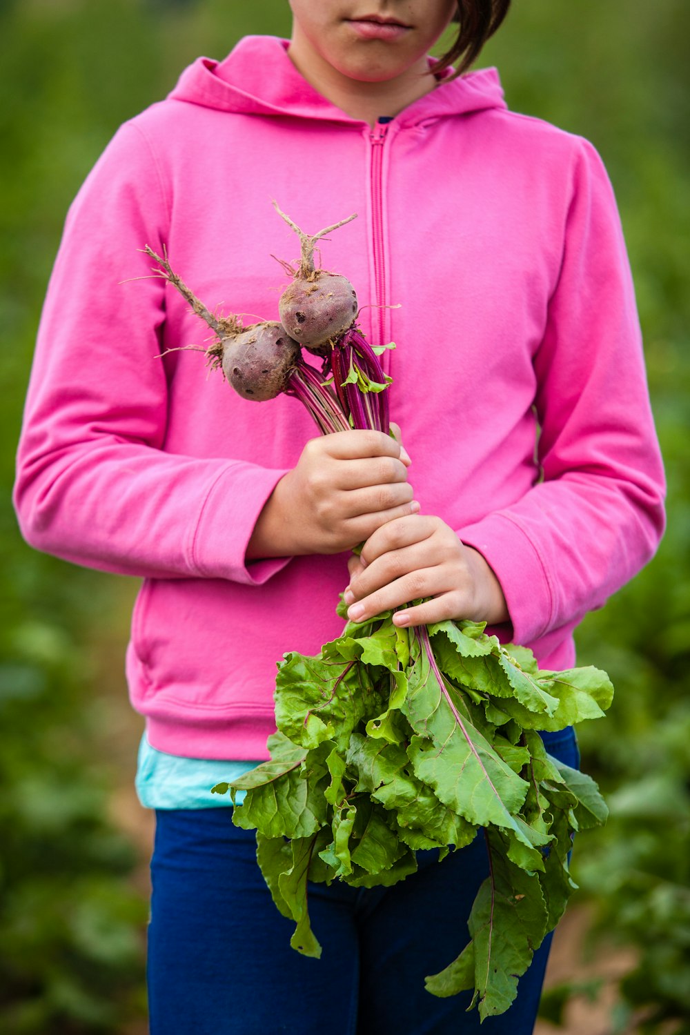 woman wearing pink jacket holding vegetable