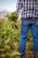 Photo of a smiling farmer standing in a lush green field holding fresh produce.