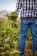 A smiling farmer standing proudly in a lush green field holding fresh produce.
