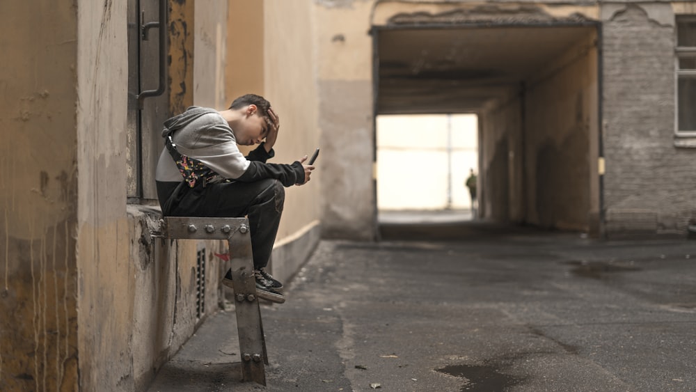 man sitting on ladder holding smartphone