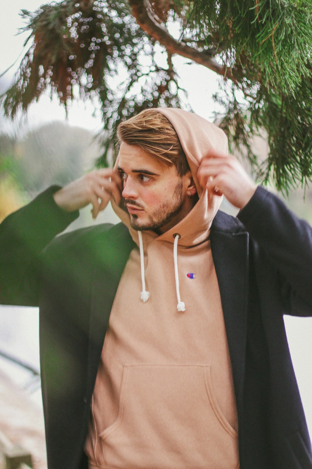 man wearing black jacket standing near tree