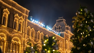A warmly lit historic Kress building decorated with Christmas lights and wreaths at dusk.