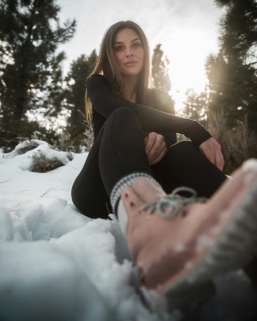 woman lying on snow near trees