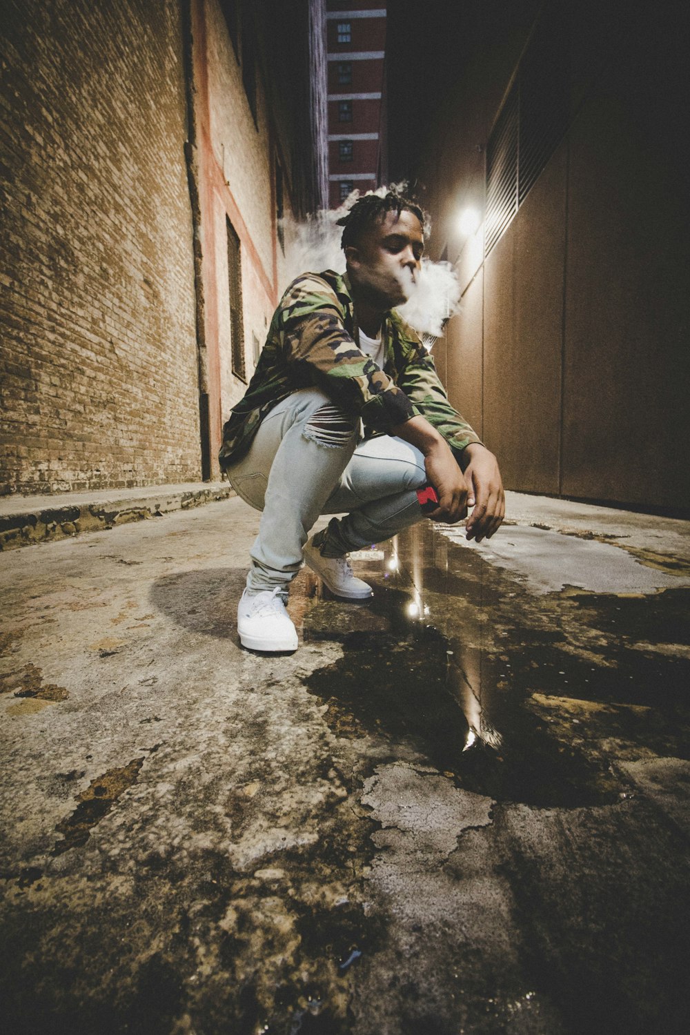 man sitting down between concrete wall