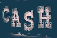 Large illuminated letters spell out the word 'CASH' against a dark background, with each letter filled with lightbulbs that produce a soft, glowing effect.