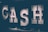 Large illuminated letters spell out the word 'CASH' against a dark background, with each letter filled with lightbulbs that produce a soft, glowing effect.