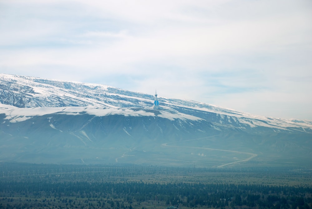 white and blue tower on top of mountain covered in snow