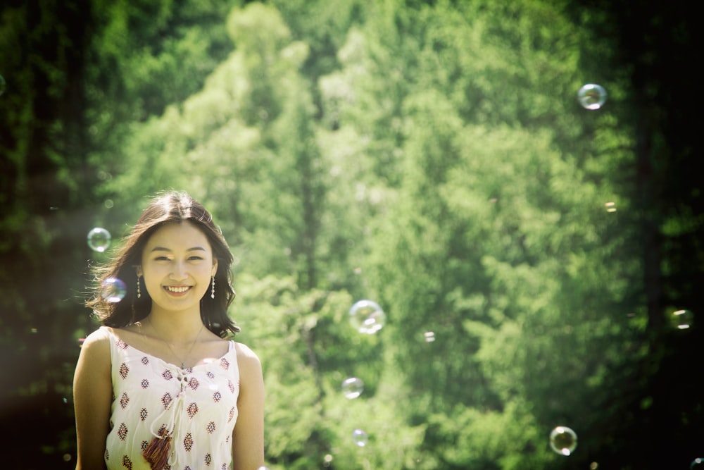 smiling woman standing neat green tree