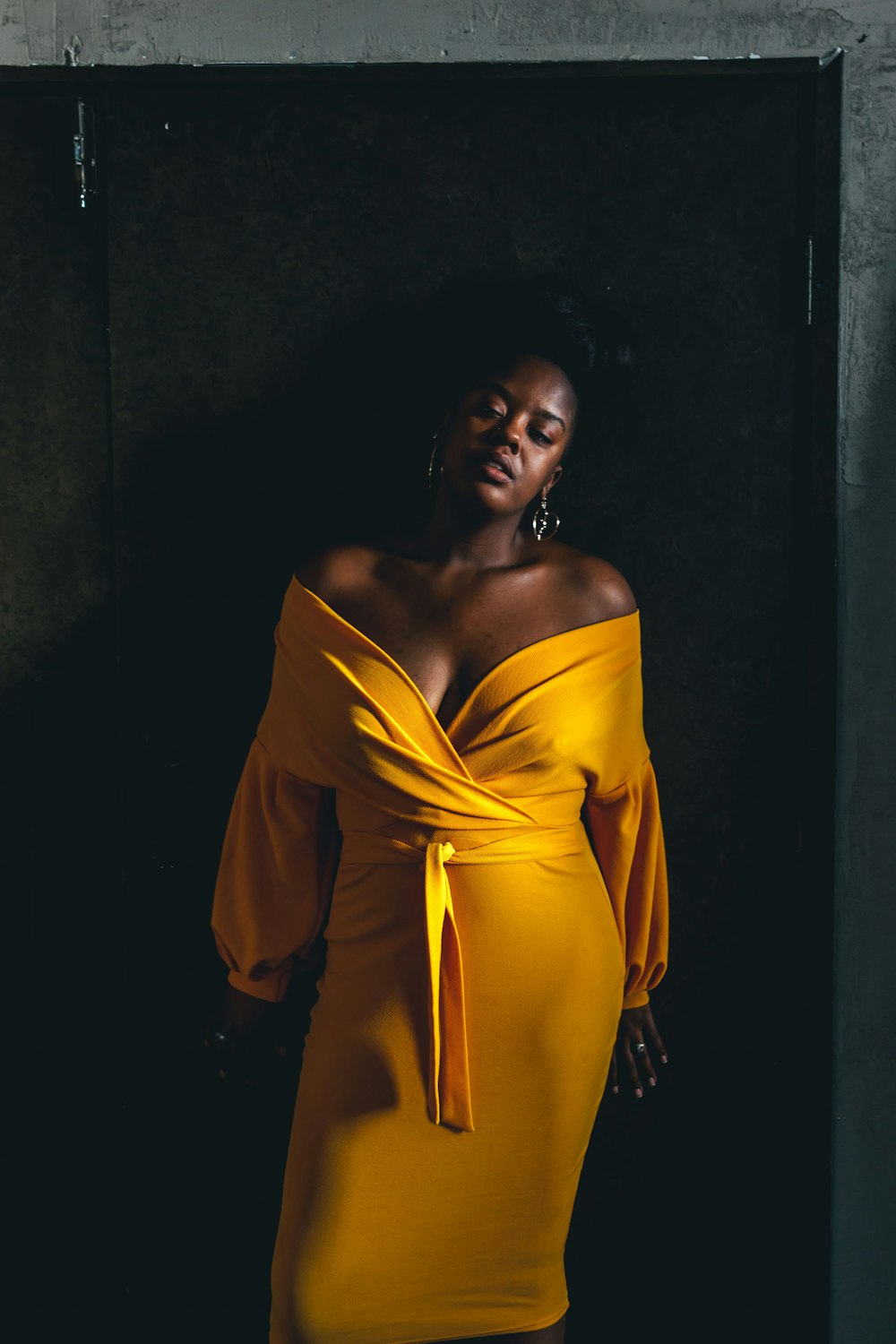 woman wearing yellow dress leaning on wall