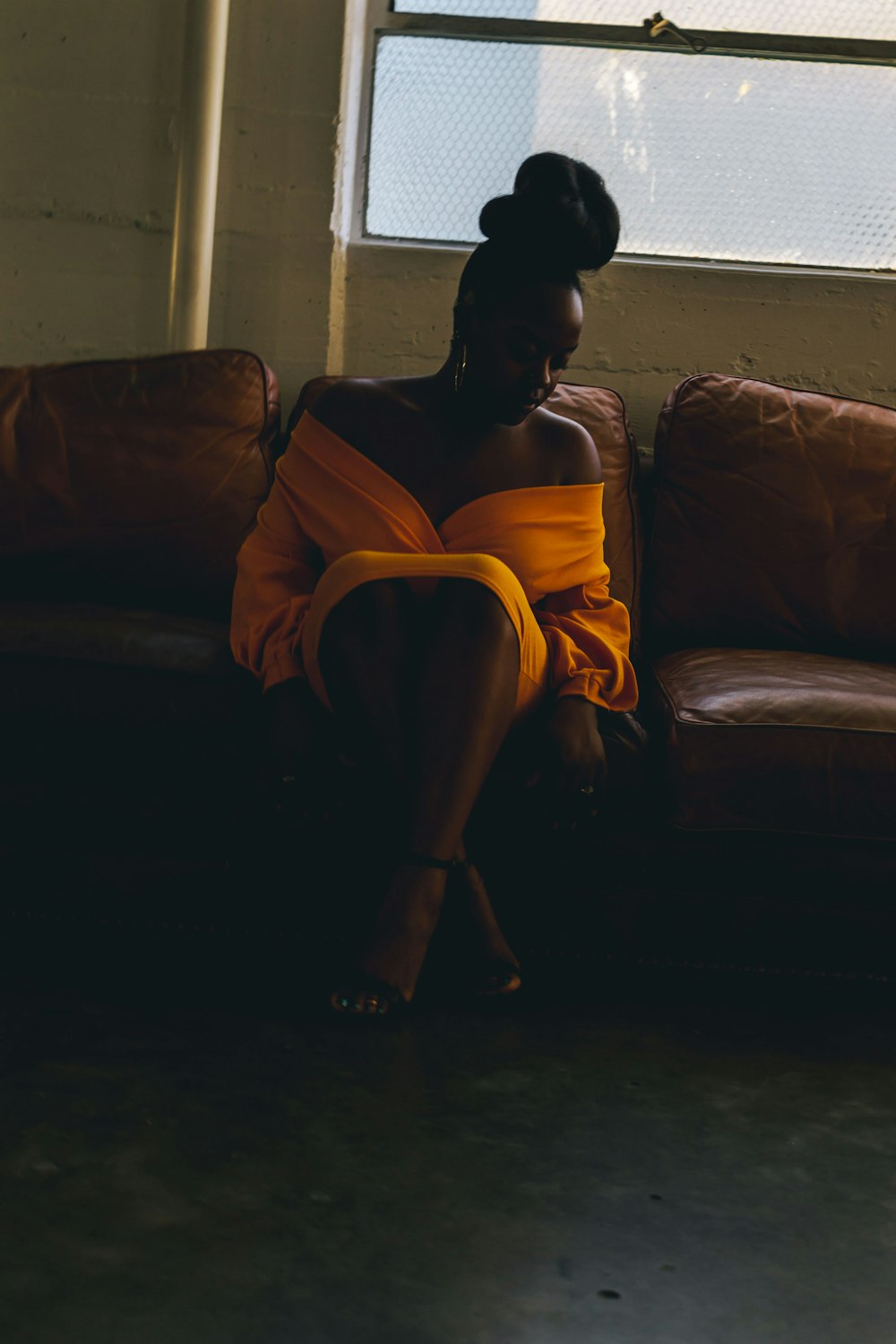 woman in yellow dress sitting on brown couch