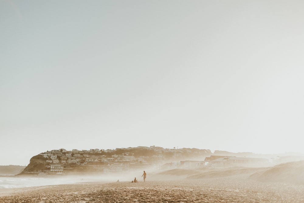 two people standing on a beach near the ocean