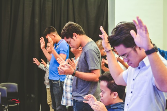 people raising hands while closing their eyes inside room