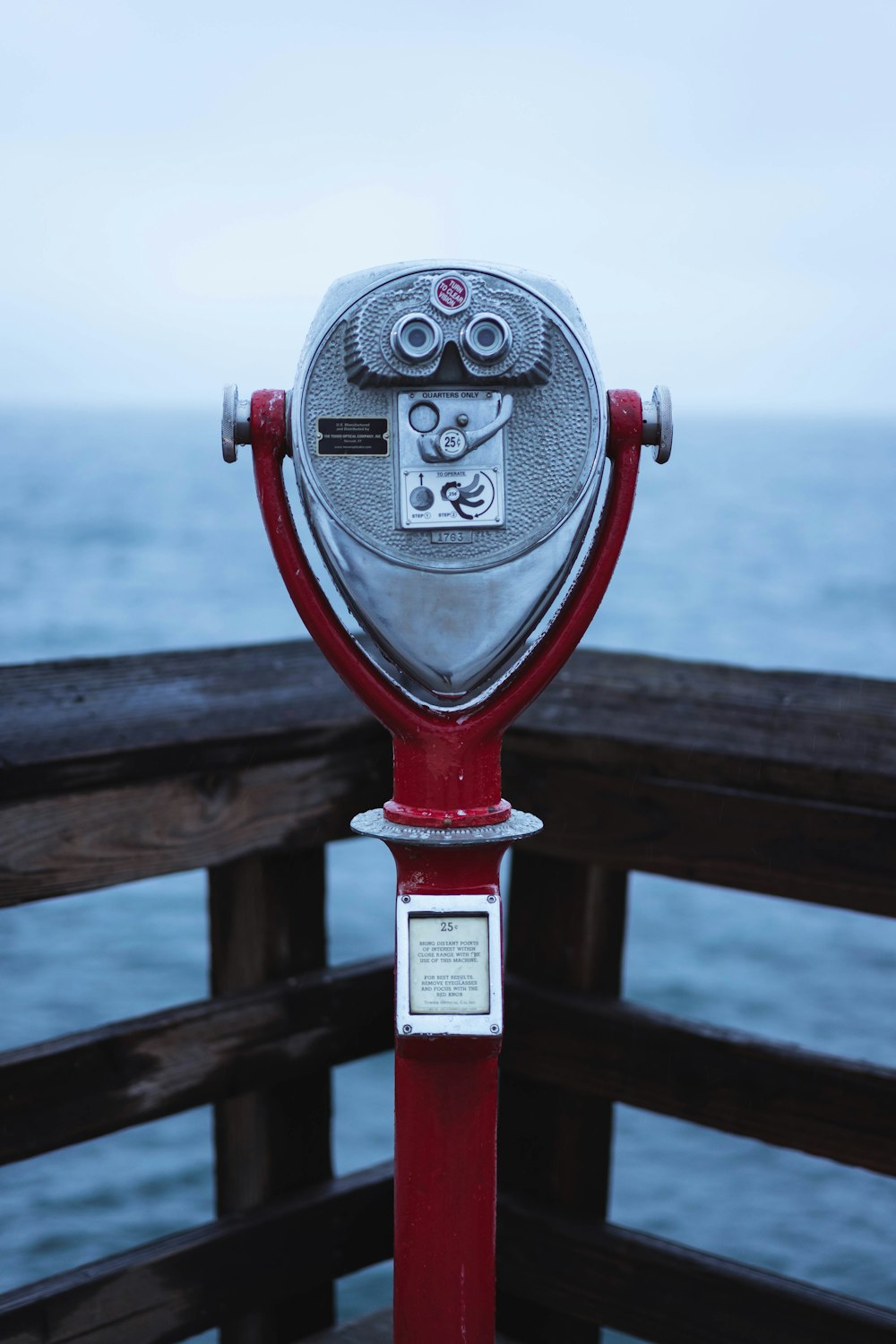 red and grey binoculars beside wood railings