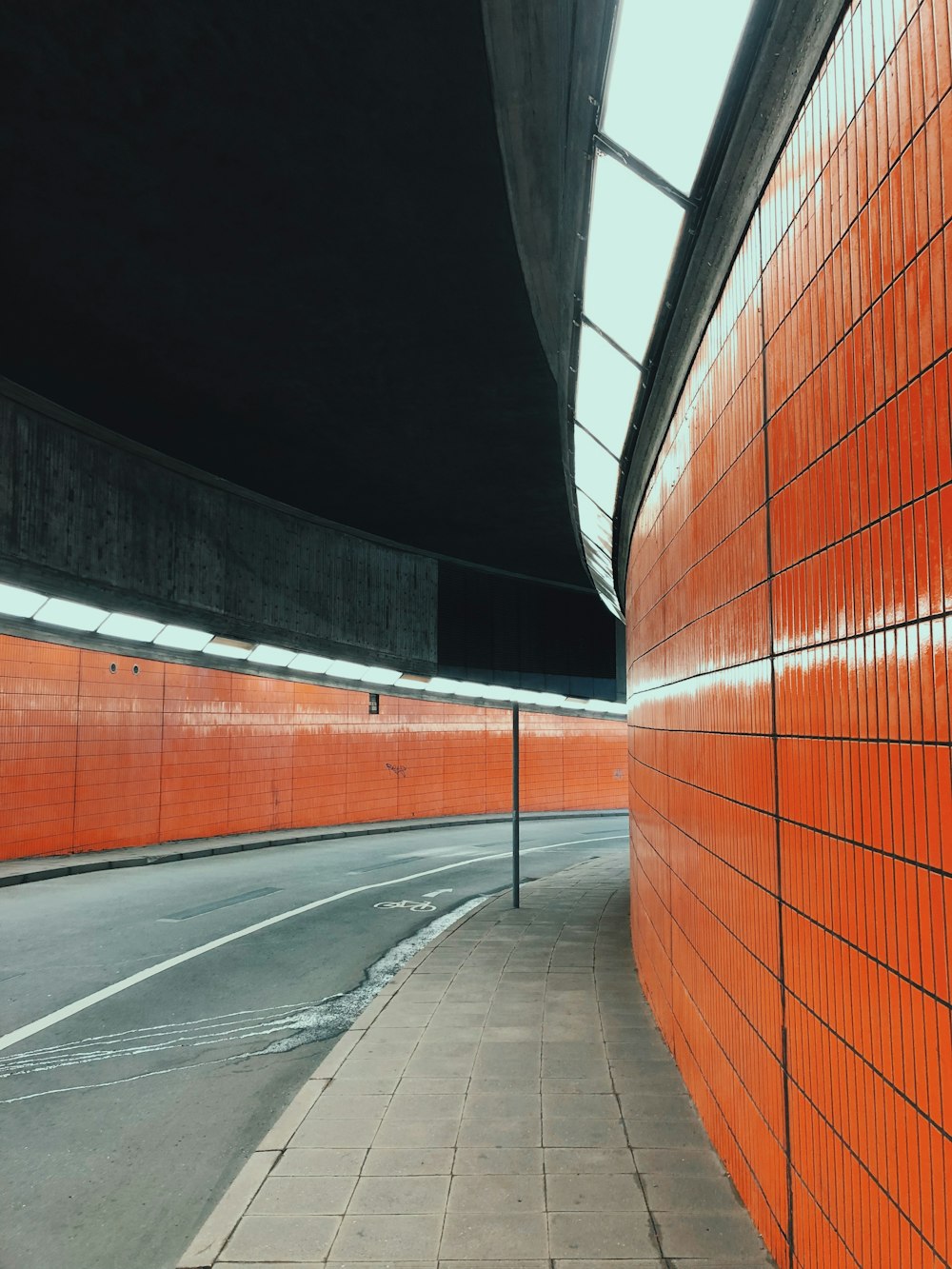 un mur orange à côté d’une rue vide