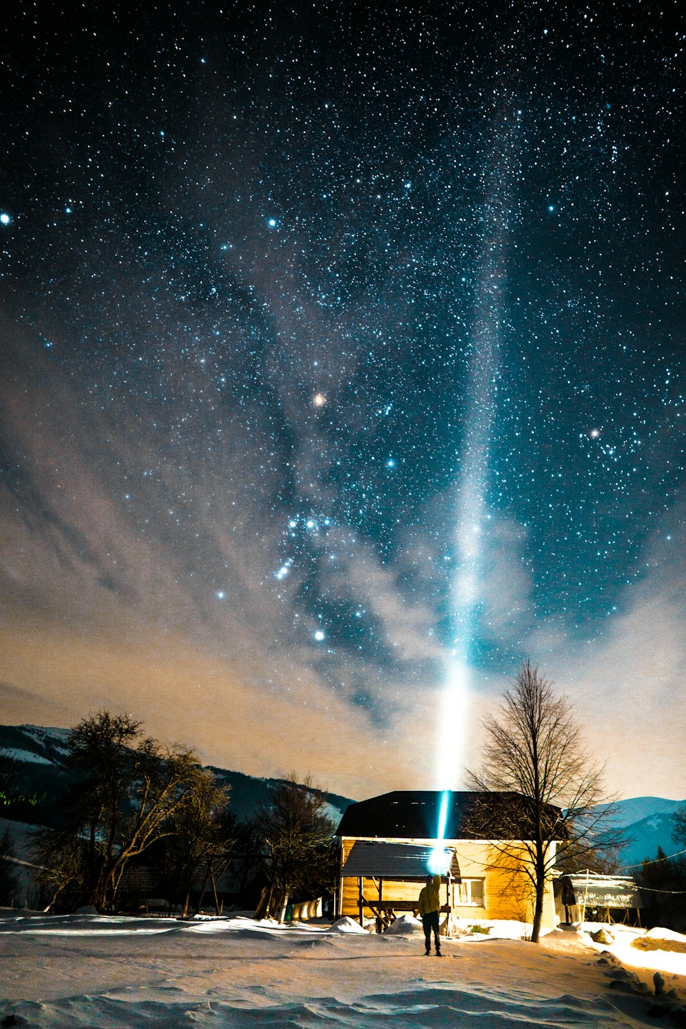 person flashing light using flashlight towards sky at night