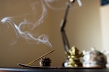 Soft smoke curling up from a lit sondhee dhoop cone in a serene indoor setting.