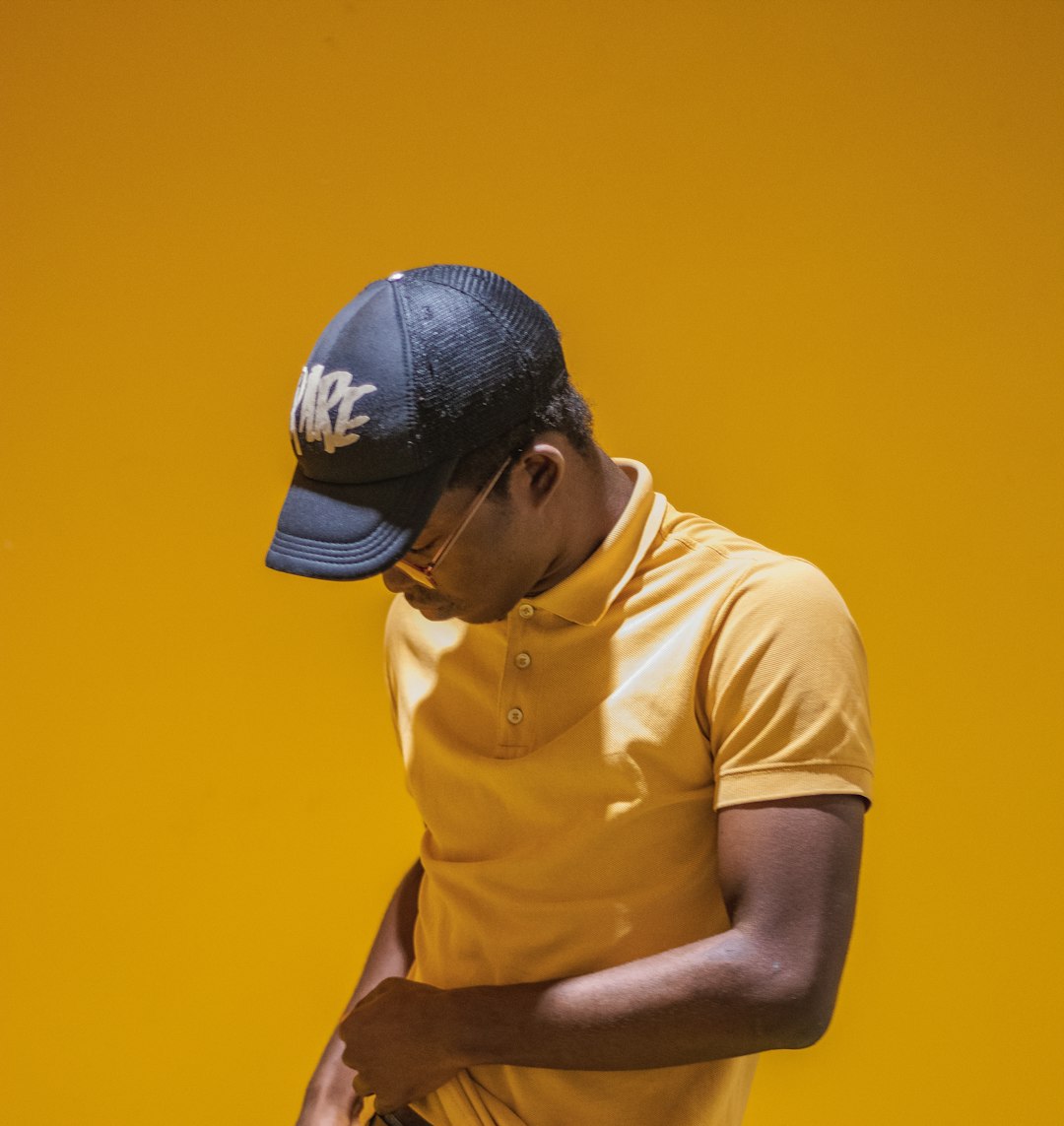 man in yellow sport shirt and black baseball cap
