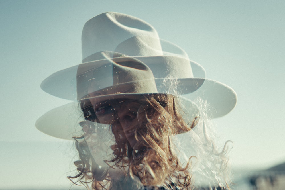 Una mujer con un sombrero con el pelo soplando en el viento