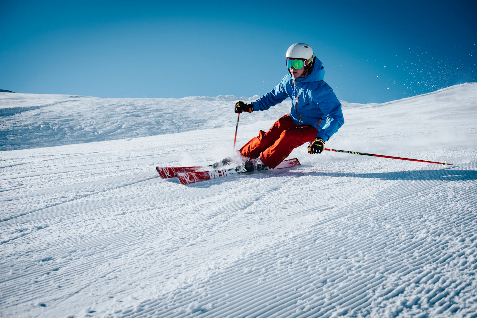 Alpinist i blå jakke i en preparert skibakke