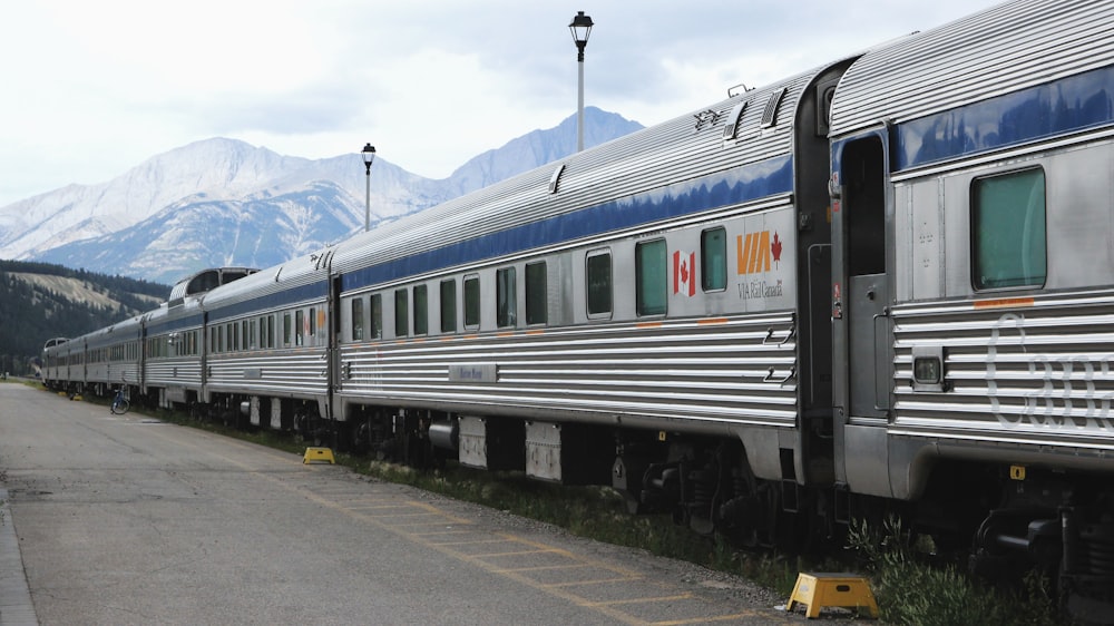 Tagsüber grauer und blauer Zug am Bahnhof