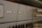 A close-up view of a network switch featuring a row of numbered indicator lights with some illuminated in white and green. The device has multiple Ethernet ports, and connectors are visible in the blurred background.