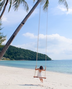 woman wearing white dress sitting on the swing