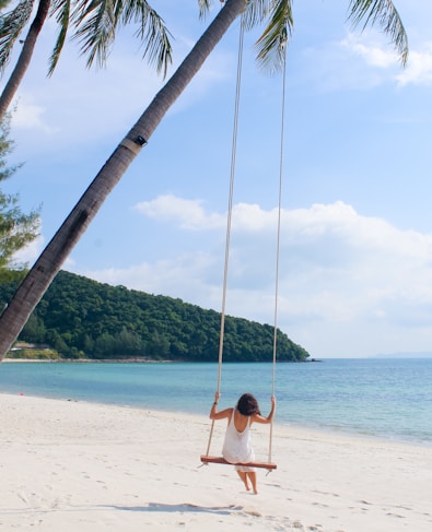 woman wearing white dress sitting on the swing