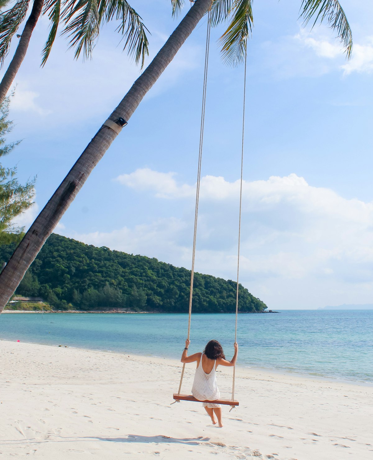 Mae Nam Koh Samui — woman on rope swing over calm tropical beach water