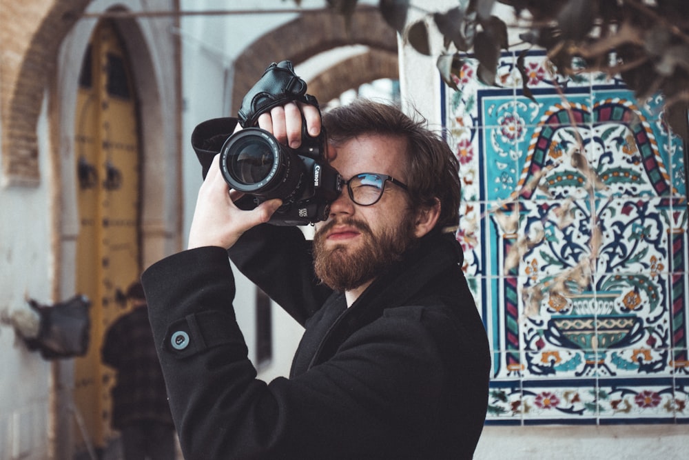 man standing and using DSLR cameta