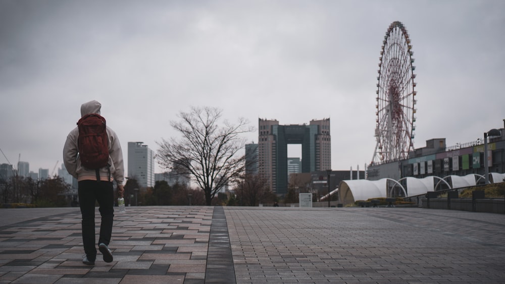 greyscale photography of man walking near the ferris wheel