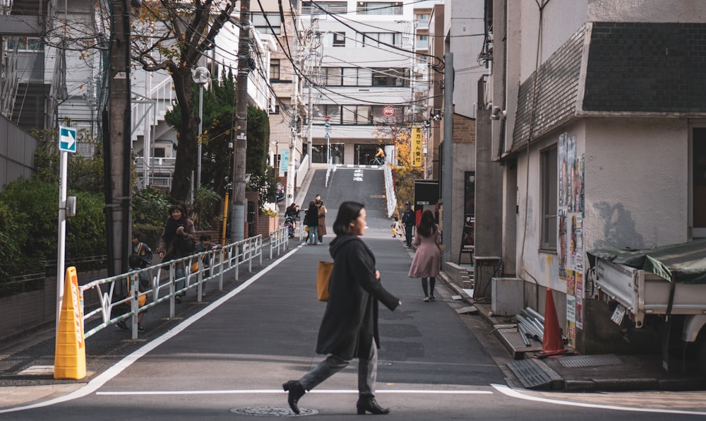 woman in black coat walking in road