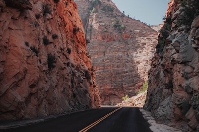 A winding trail through towering red rock formations with sparse desert vegetation.