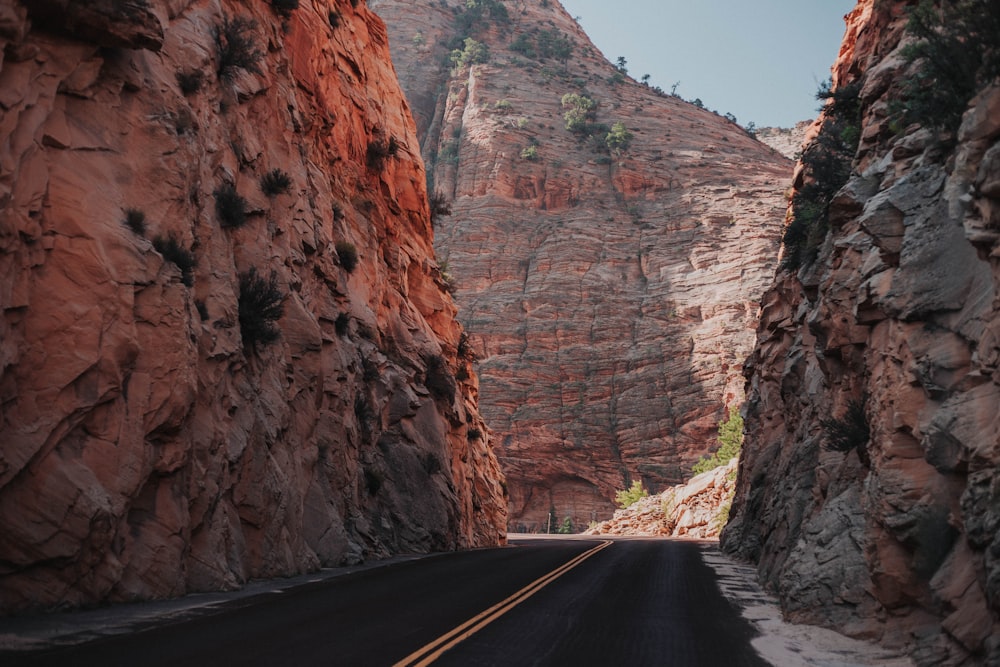 narrow roadway in between tall mountain during daytime