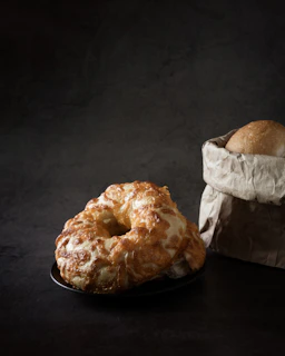 Freshly baked bagels and toast artfully arranged on a light caramel wooden table.