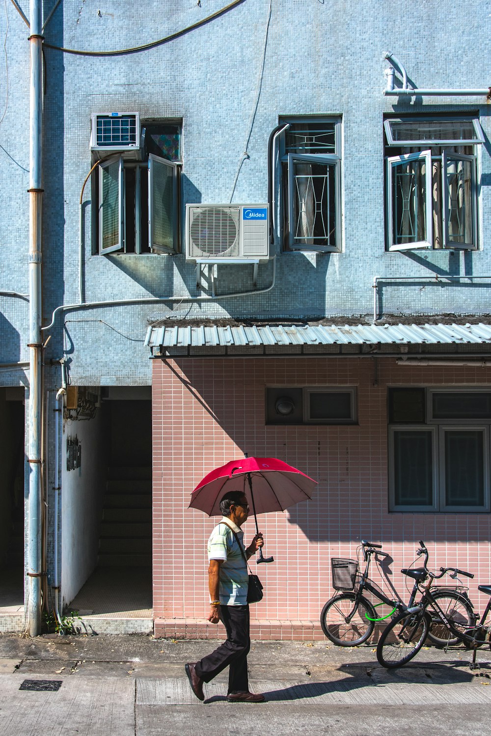 Person unter rotem Regenschirm geht tagsüber spazieren