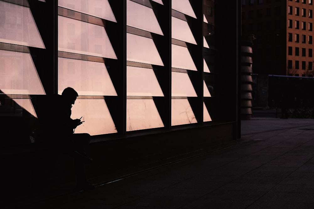 a man sitting in front of a window looking at his cell phone