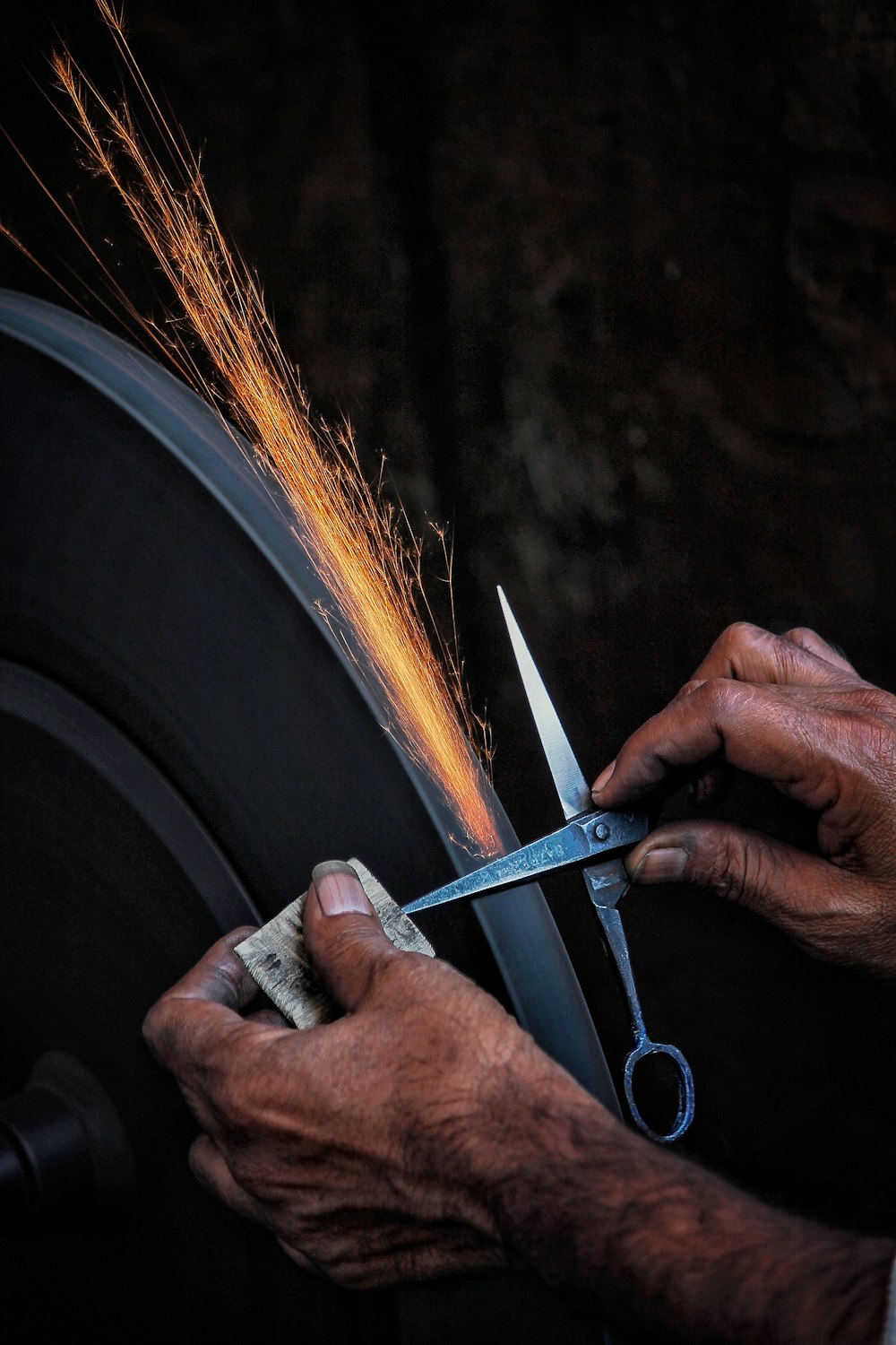 person sharpening gray scissors