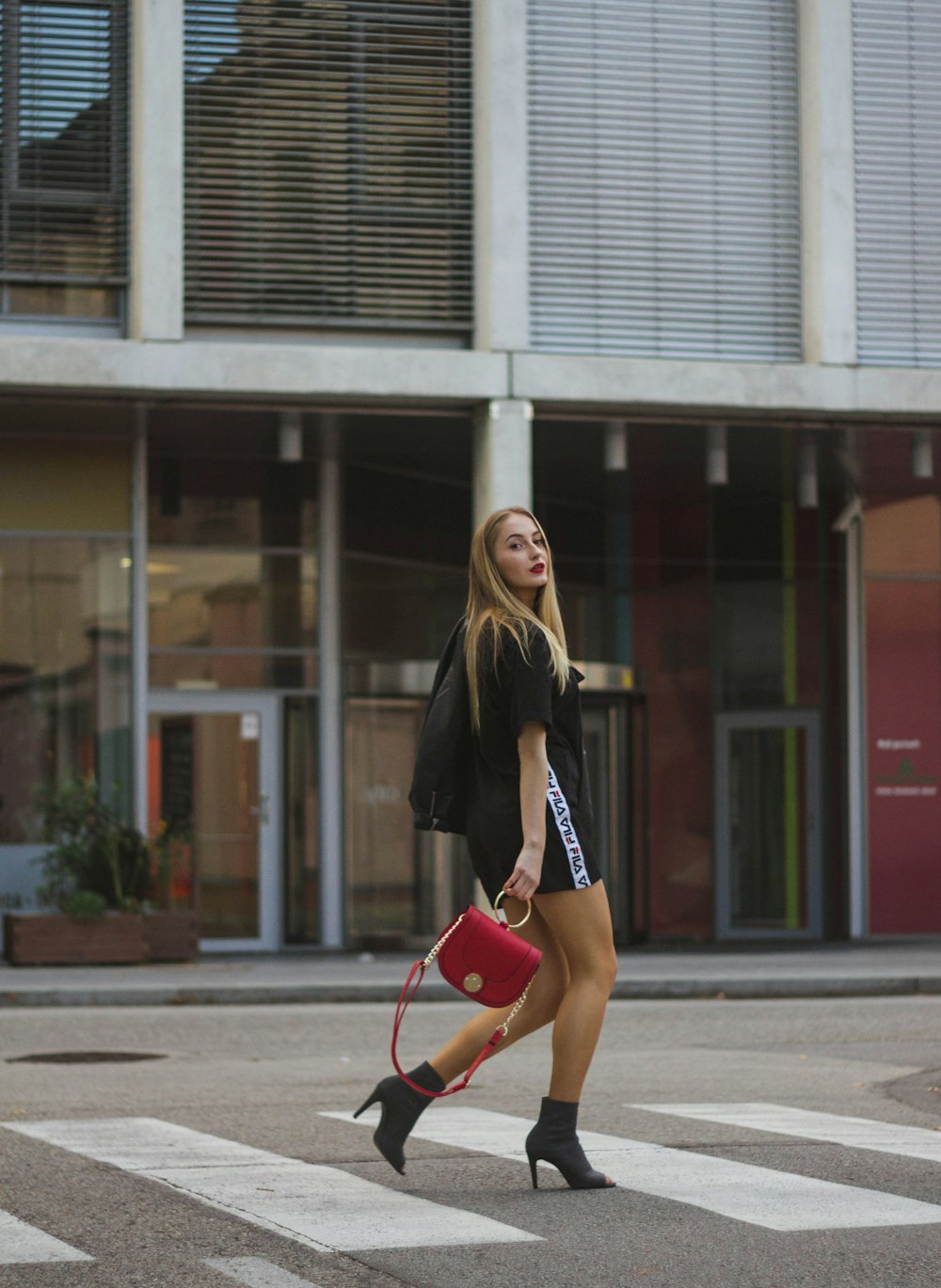 woman in black shirt walking beside white building