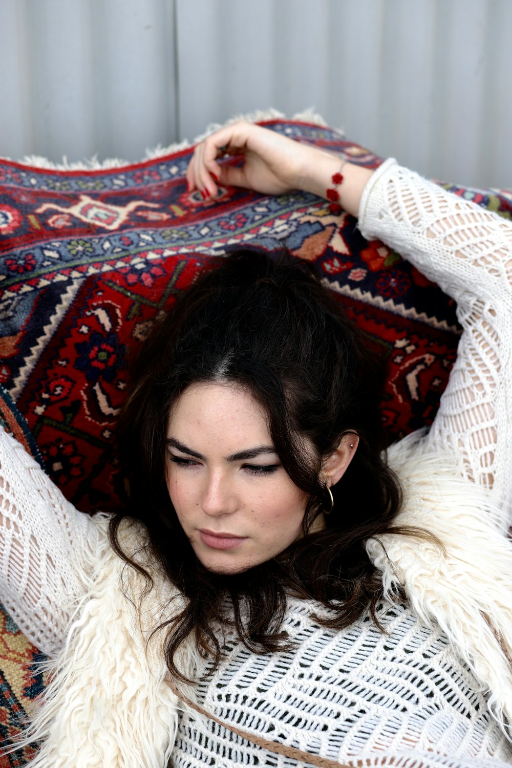 woman lying on red and blue floral area rug