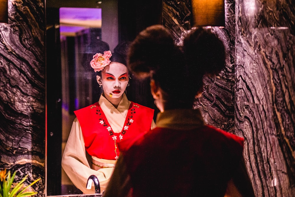 woman in red and beige costume facing mirror