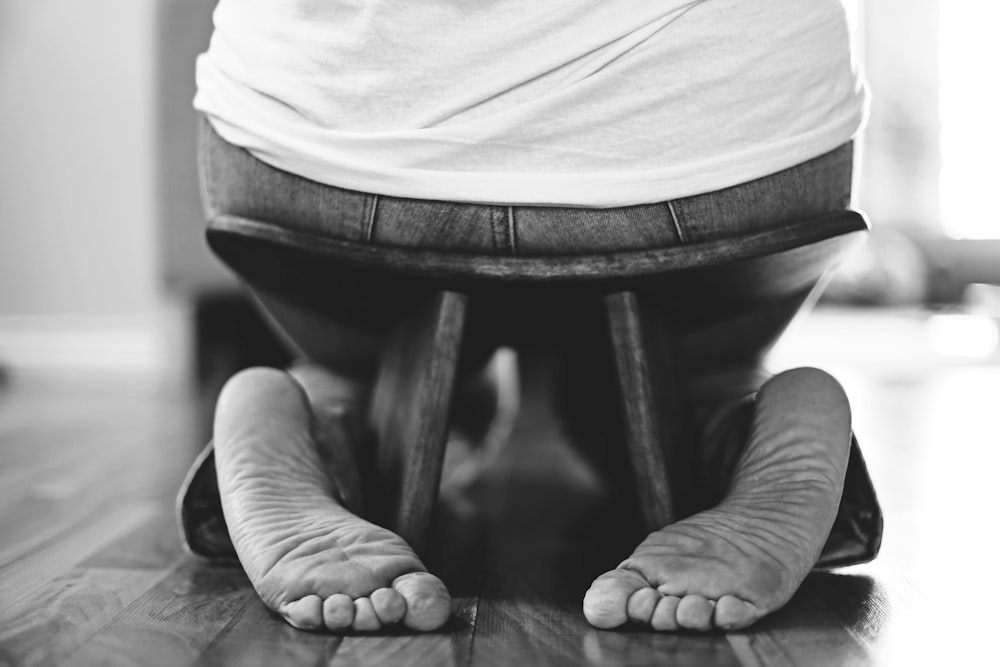 grayscale photography of person sitting on stool