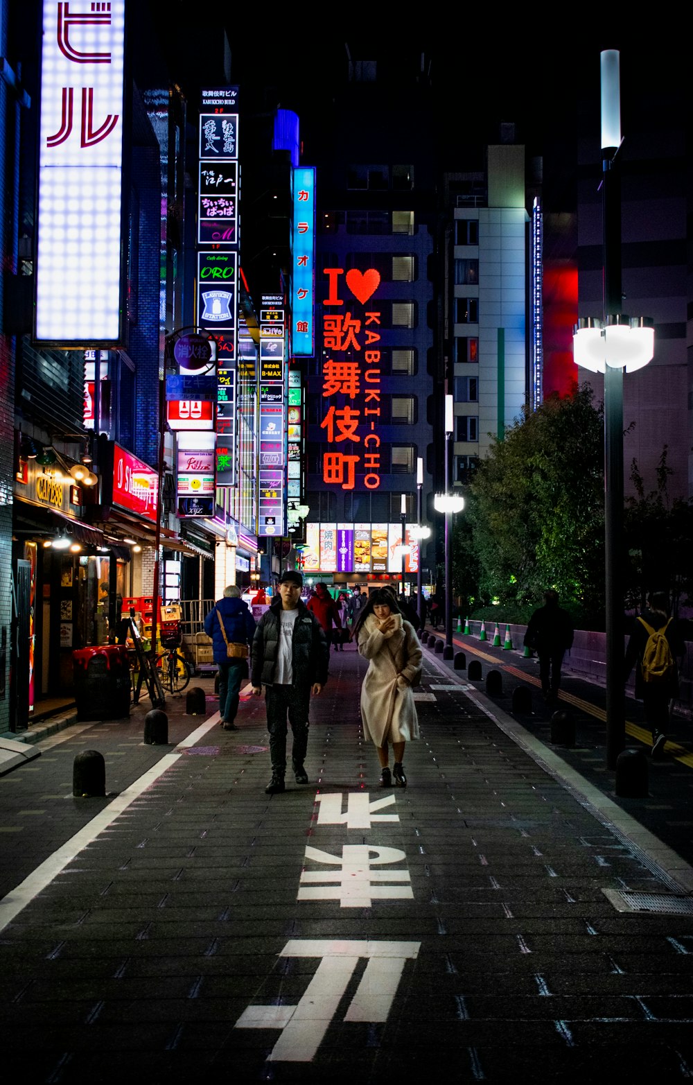 man standing beside woman on street at night